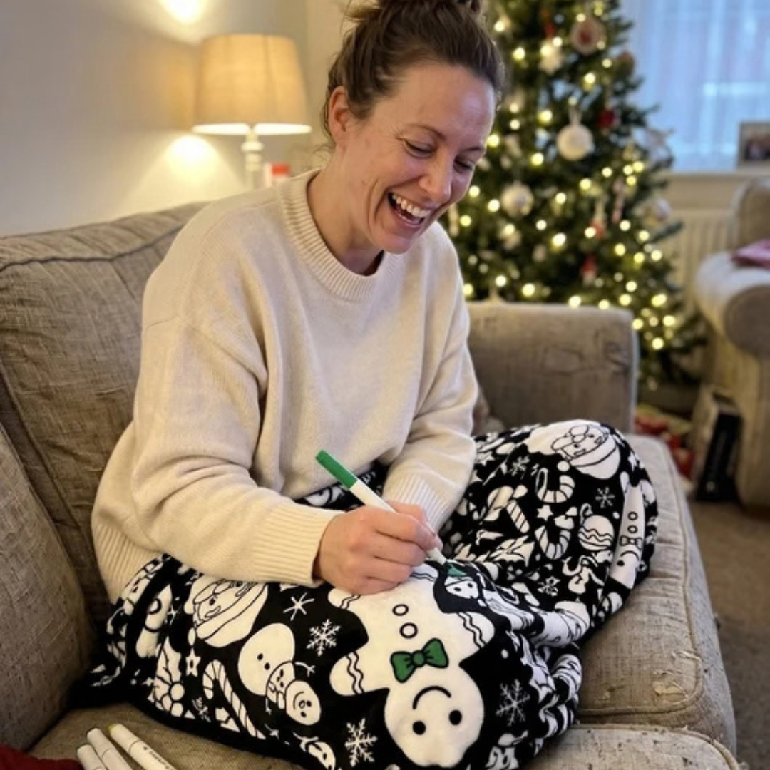Woman coloring the blanket on a sofa by the Christmas tree
